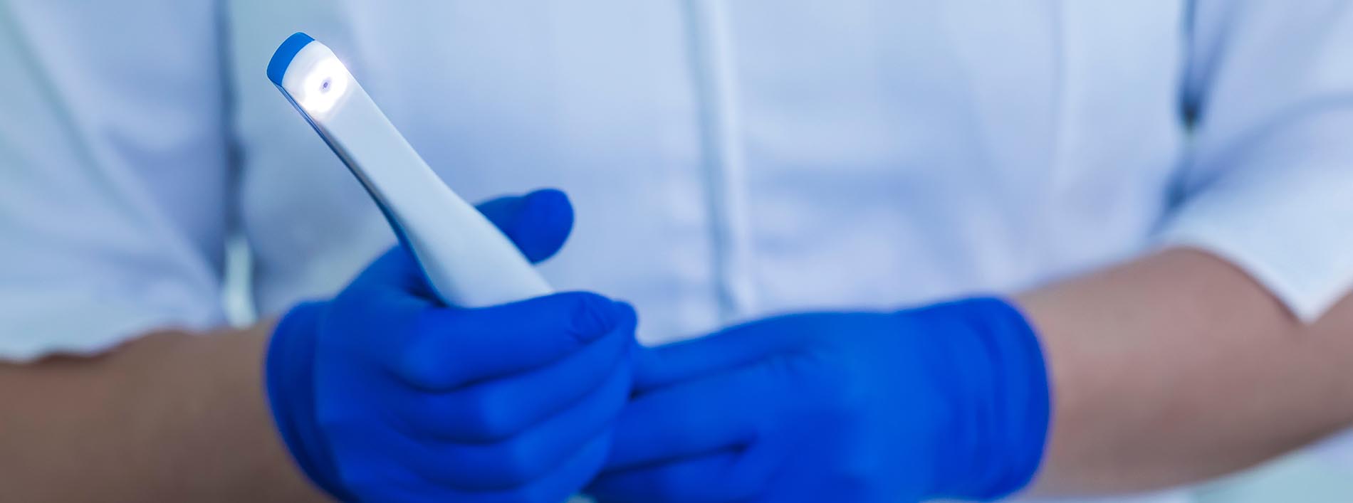 The image shows a person wearing blue gloves and holding a smartphone with a white cover.