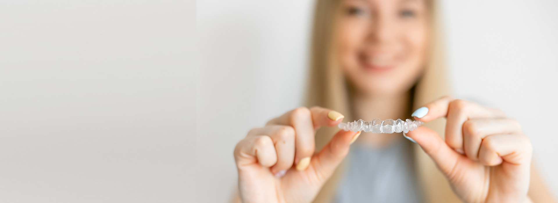 A woman holding a small object, possibly jewelry or an award, against a blurred background.