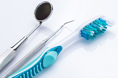 The image features a collection of dental instruments and tools, including a toothbrush with blue bristles, set against a white background.