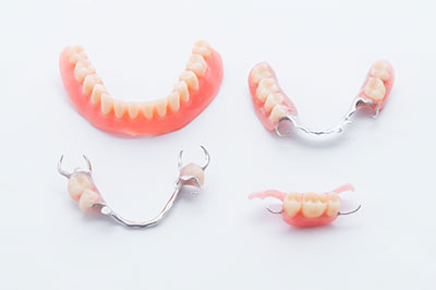 Alt text   A set of dental implants with pink resin teeth and silver brackets displayed against a white background.