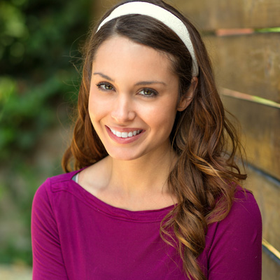 A woman with long hair and a headband smiles at the camera.