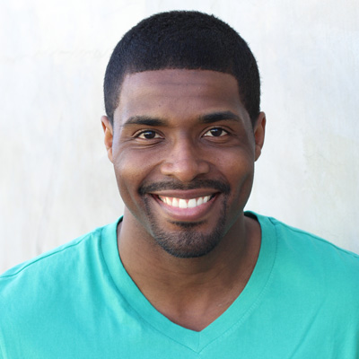 A man and a woman are smiling and embracing each other in an outdoor setting.