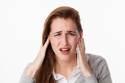 A young woman with hand on her head, appearing to be in pain or distress.