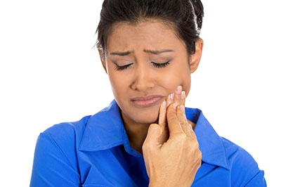 A woman with a concerned expression is seen holding her hand to her face, possibly indicating pain or discomfort.