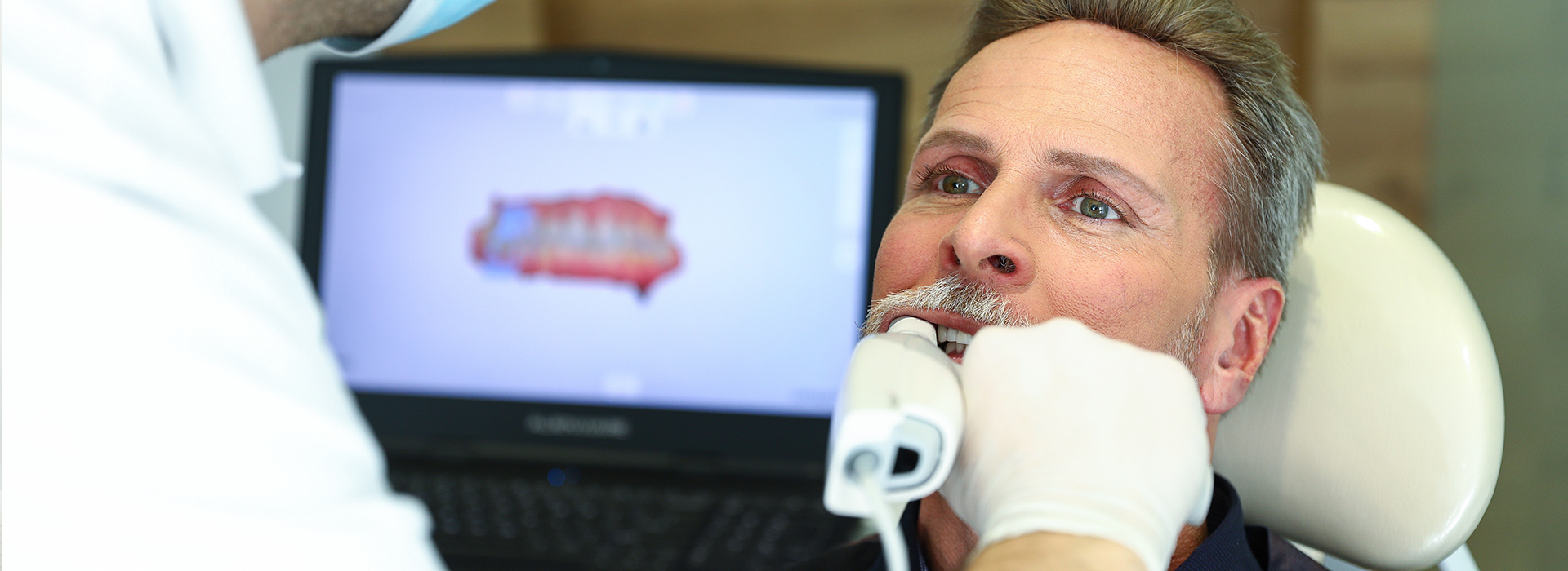 The image depicts a scene in a dental office where a man is receiving a dental implant procedure.