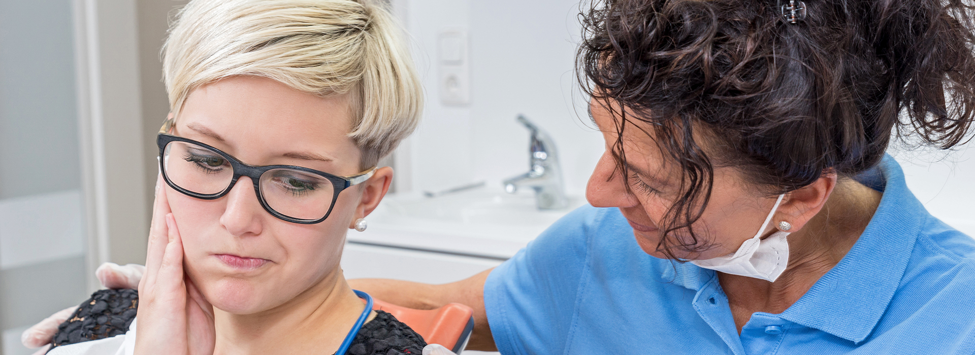 A woman receiving a dental cleaning from a professional in an office setting.