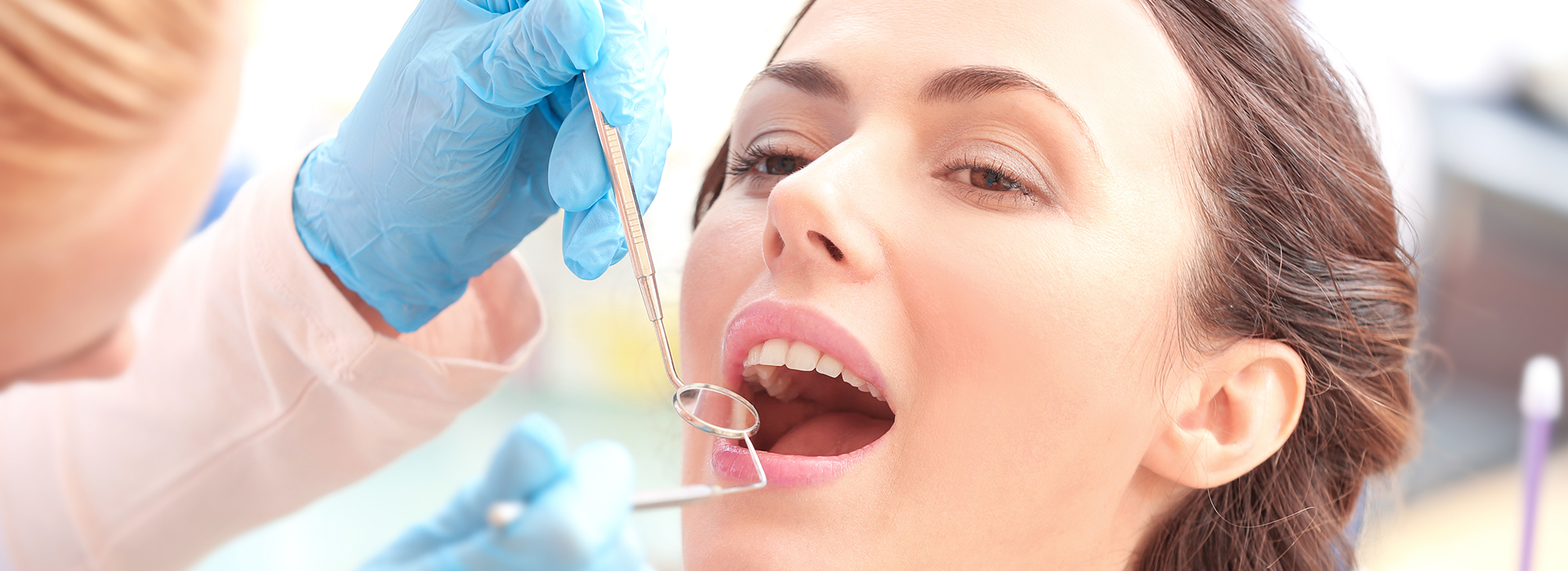 A dental professional performing a teeth cleaning procedure on a patient, with the patient s mouth open and a dental tool in action.