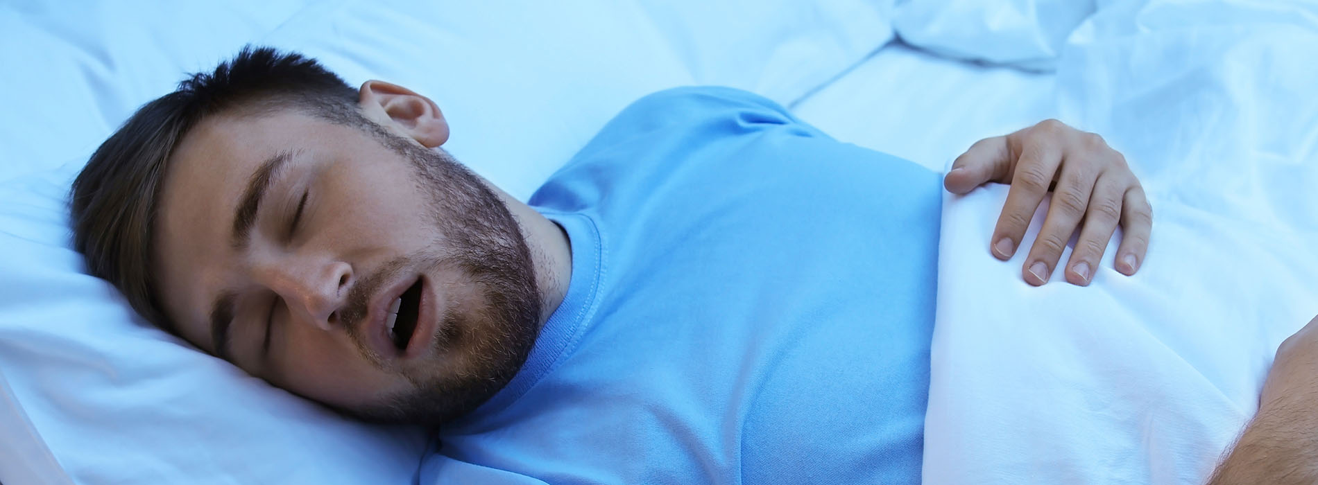 A man in a hospital bed, with his eyes closed and mouth open as if he s asleep or possibly in pain.