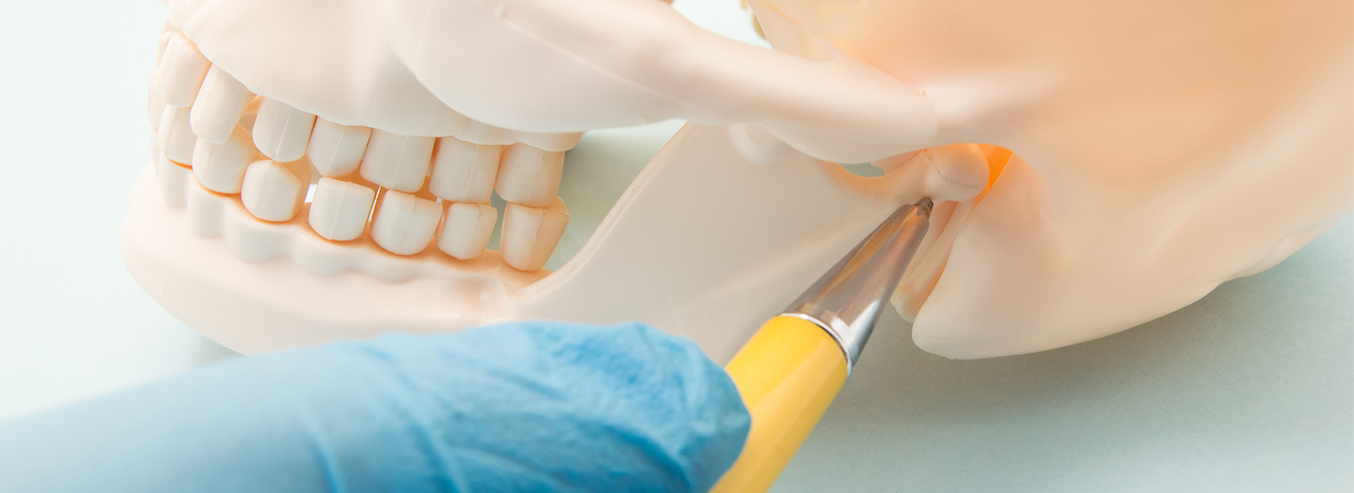 An image of a dental procedure in progress, featuring a tooth being prepared for implantation with a surgical instrument and a yellow tool.