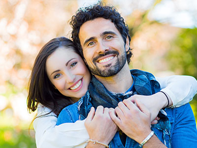 A man and a woman, both smiling, posing for a photograph with the man s arm around the woman.