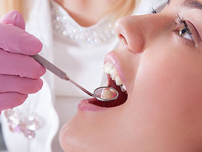 A dental professional using a drill to perform oral surgery on a patient.