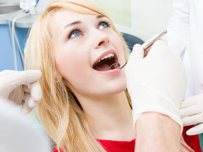 A woman in a dental chair, receiving dental care with a smile.