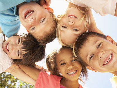 Children of various ages and ethnicities smiling together in a group photo.