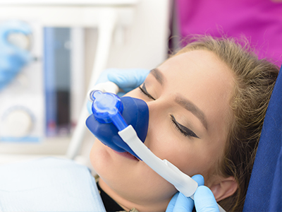 A woman receiving an oxygen treatment, with a medical professional applying the mask to her face.