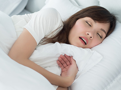 A woman is peacefully sleeping with her eyes closed, her mouth slightly open, and her head resting on a pillow.