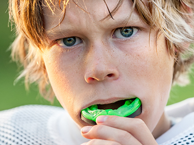 A young boy with a mouthguard is blowing bubbles, capturing the moment in a close-up shot.